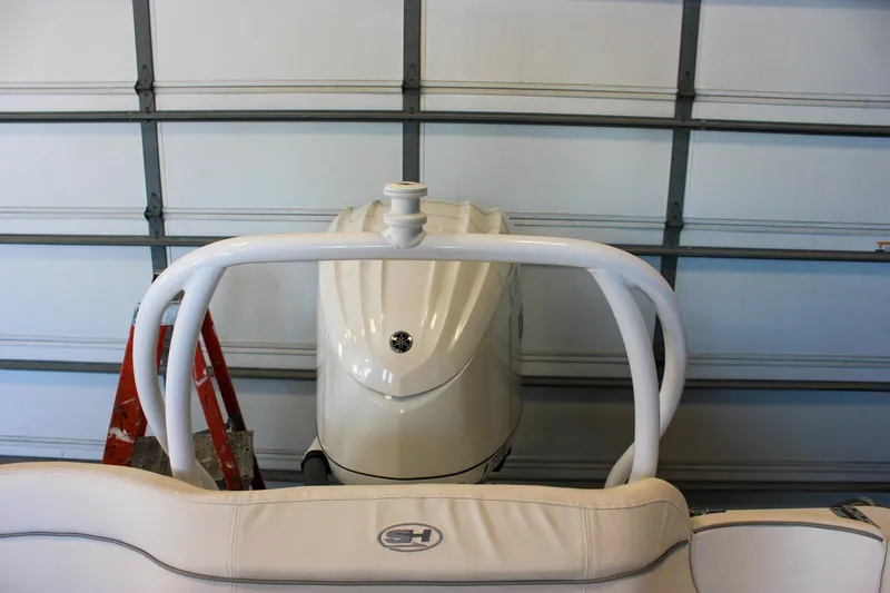 Slide: The Image of 2025 Sea Hunt Ultra 239 SE boat in garage, rear view with engine and ladder. - 11