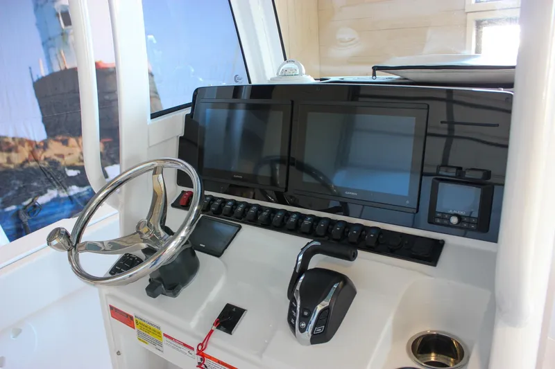 Slide: The Image of 2025 Sea Hunt Ultra 239 SE boat dashboard with dual screens and steering wheel. - 37