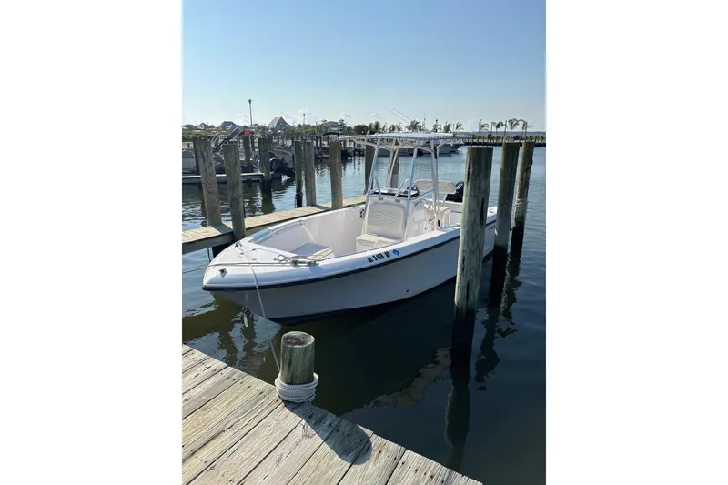 Slide: The Image of 2023 Aquasport 22CC boat docked at a marina on a sunny day. - 3