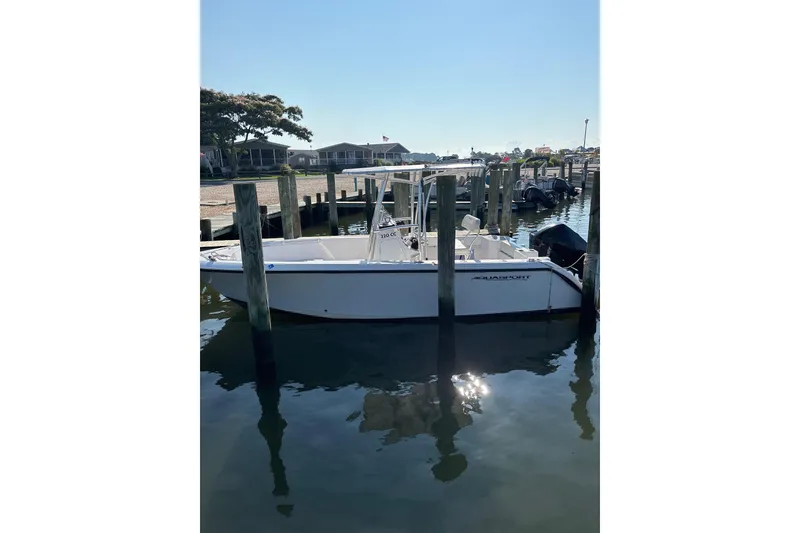 Slide: The Image of 2023 Aquasport 22CC boat docked at a marina, reflecting on calm water. - 4