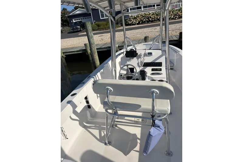 Slide: The Image of 2023 Aquasport 22CC boat interior with steering console and seating at dock. - 5