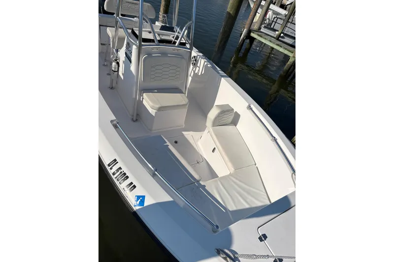 Slide: The Image of 2023 Aquasport 22CC boat interior with seating and console, docked by the water. - 7