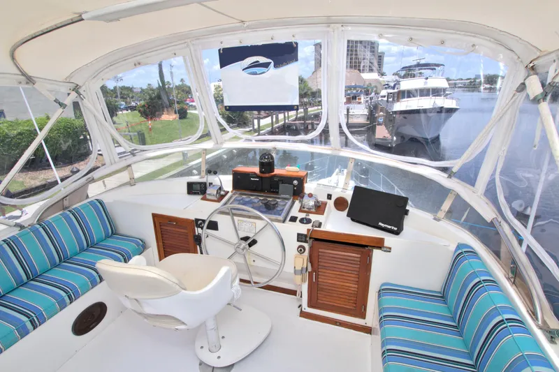 Slide: The Image of 1987 Jefferson 42 Sundeck yacht interior with striped seating, steering wheel, and dockside view. - 16