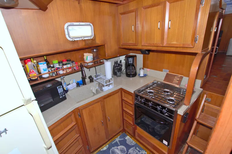 Slide: The Image of 1987 Jefferson 42 Sundeck yacht kitchen with wooden cabinets, stove, and appliances. - 33