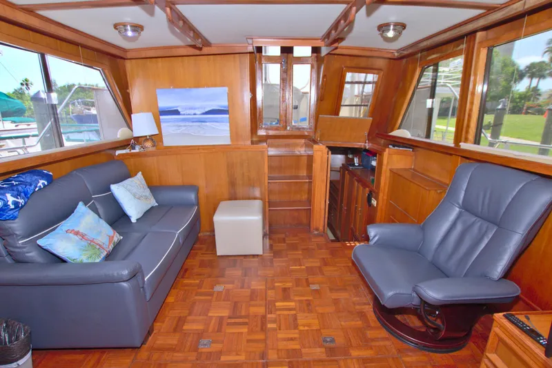 Slide: The Image of 1987 Jefferson 42 Sundeck interior with wood paneling, blue seating, and large windows. - 42