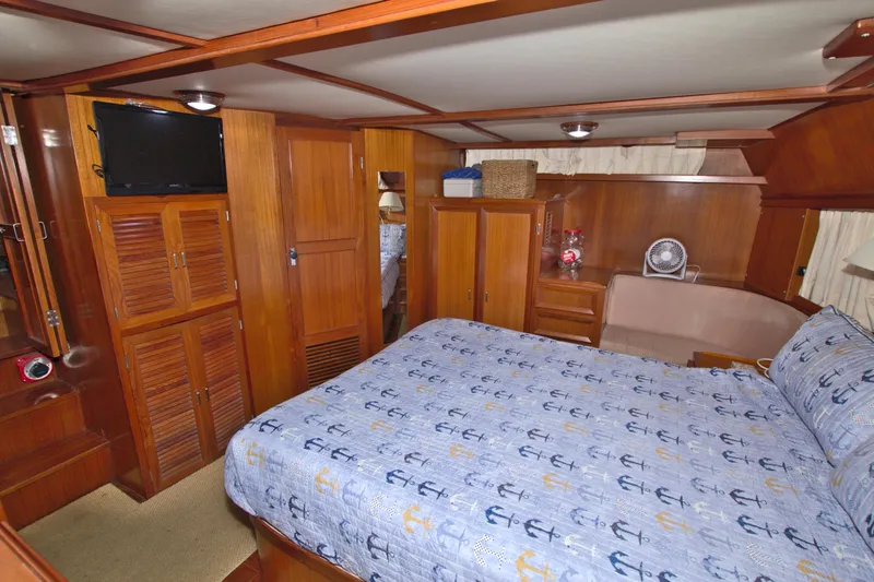 Slide: The Image of 1987 Jefferson 42 Sundeck yacht bedroom with wood paneling and anchor-patterned bedding. - 45