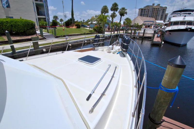 Slide: The Image of 1987 Jefferson 42 Sundeck yacht docked at marina with clear sky and palm trees. - 6