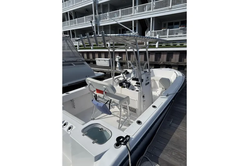 Slide: The Image of 2023 Aquasport 22CC boat docked, featuring center console and seating, in marina setting. - 3