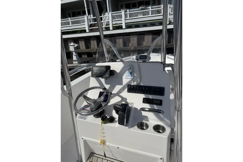 Slide: The Image of 2023 Aquasport 22CC boat console with steering wheel and controls, docked near a building. - 5