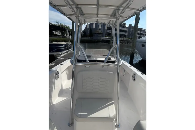 Slide: The Image of 2023 Aquasport 22CC boat interior with seating and console, docked near waterfront homes. - 6