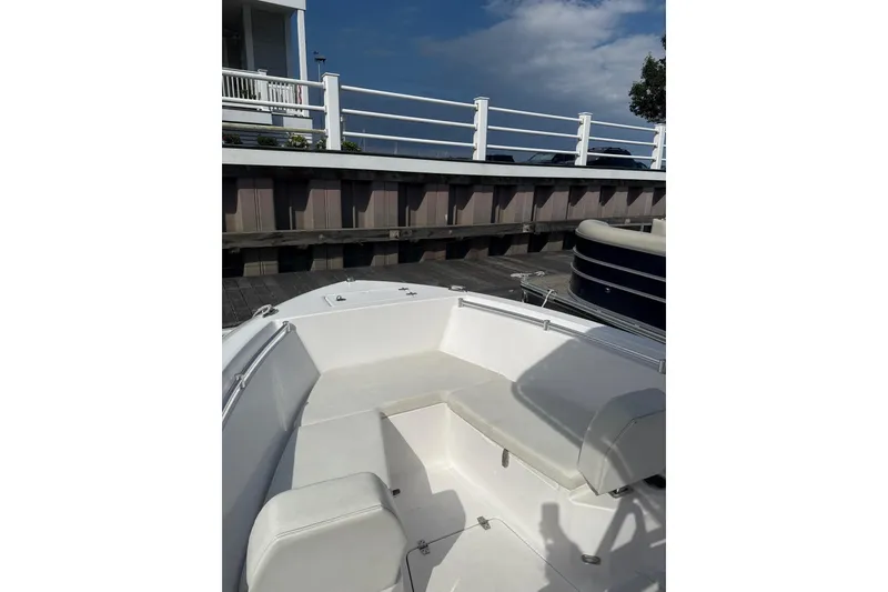 Slide: The Image of 2023 Aquasport 22CC boat interior with white seating, docked by a wooden pier. - 7