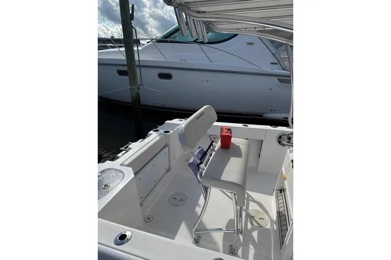 Slide: The Image of 2023 Aquasport 22CC boat interior with seating and storage, docked beside another vessel. - 8