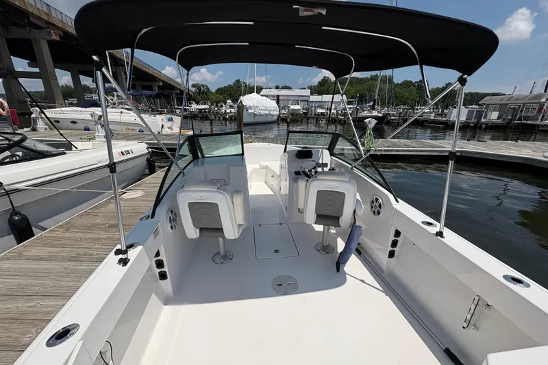 Slide: The Image of 2023 Aquasport 22CC boat docked at marina, featuring spacious deck and canopy. - 5