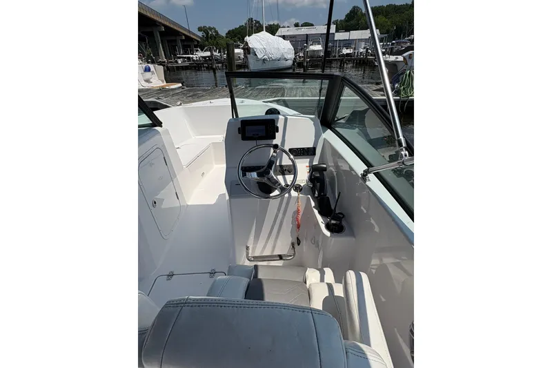 Slide: The Image of 2023 Aquasport 22CC boat interior with steering wheel and controls at marina. - 7