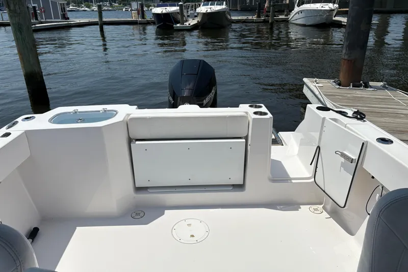 Slide: The Image of 2023 Aquasport 22CC boat interior with seating and motor, docked at marina. - 8