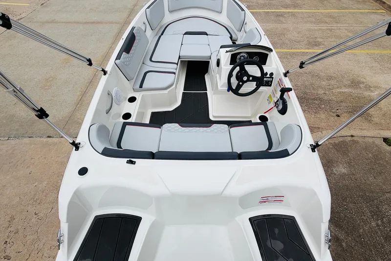Slide: The Image of 2023 Bayliner Element M15 boat interior with seating and steering wheel, docked on concrete. - 12