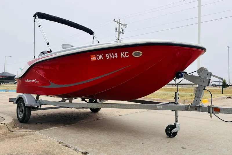 Slide: The Image of 2023 Bayliner Element M15 boat on trailer, vibrant red hull, parked outdoors. - 5