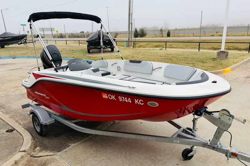 Slide: The Image of 2023 Bayliner Element M15 boat in red on a trailer, parked outdoors. - 6