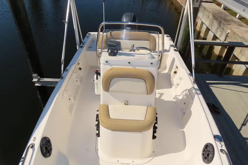 Slide: The Image of 2018 Key West 1720 Center Console boat docked, featuring beige seating and steering console. - 4