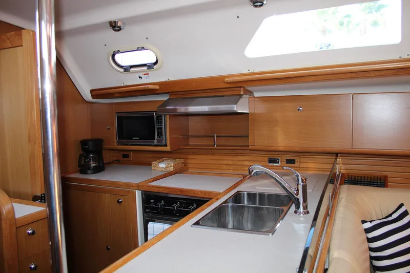 Slide: The Image of 2011 Catalina 445 yacht interior kitchen with wooden cabinetry, sink, and appliances. - 12