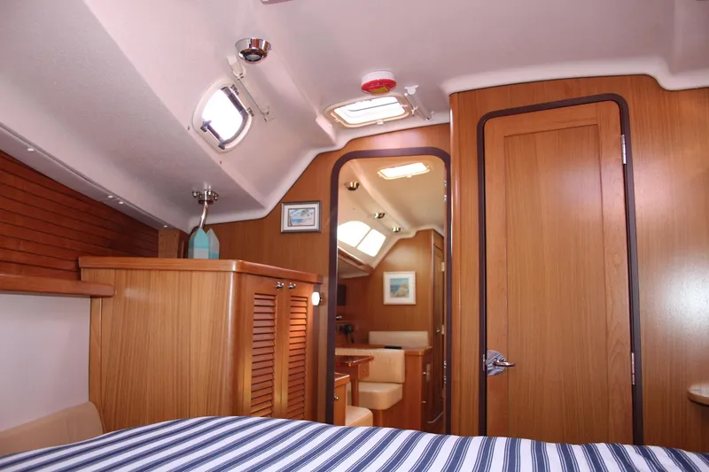 Slide: The Image of Interior of 2011 Catalina 445 sailboat with wood paneling and striped bedding. - 8