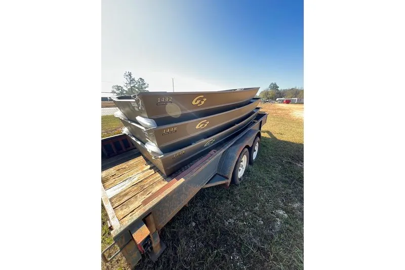 Slide: The Image of 2026 G3 1448 LW boats stacked on a trailer in a grassy area. - 3