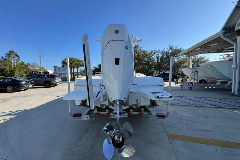 Slide: The Image of 2026 Caymas 26 HB boat on trailer, rear view with outboard motor, in sunny dealership lot. - 14