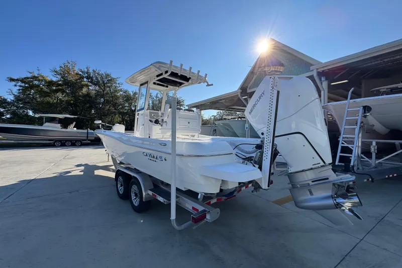 Slide: The Image of 2026 Caymas 26 HB boat with Mercury engine on trailer, parked outdoors. - 16