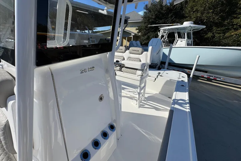 Slide: The Image of 2026 Caymas 26 HB boat interior with seating and console, parked outdoors. - 25