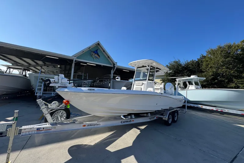 Slide: The Image of 2026 Caymas 26 HB boat on trailer, parked outside a marina under clear blue sky. - 3