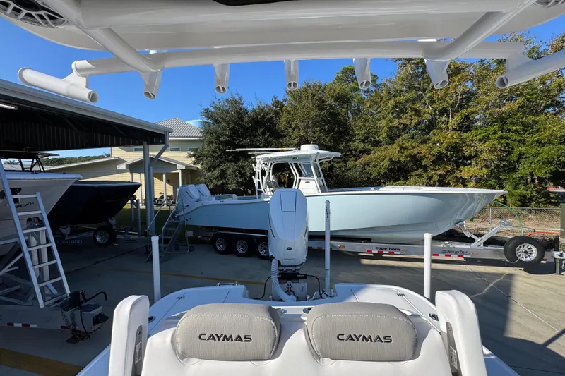 Slide: The Image of 2026 Caymas 26 HB boat on trailer, parked outdoors near trees and buildings. - 31