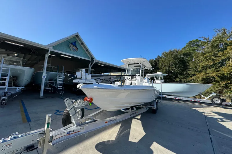 Slide: The Image of 2026 Caymas 26 HB boat on trailer outside a showroom under clear blue sky. - 4
