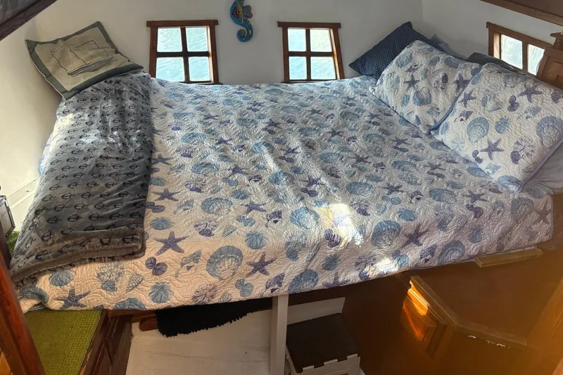 Slide: The Image of Cozy cabin bedroom in 1972 Islander 40MS sailboat with nautical-themed bedding. - 11