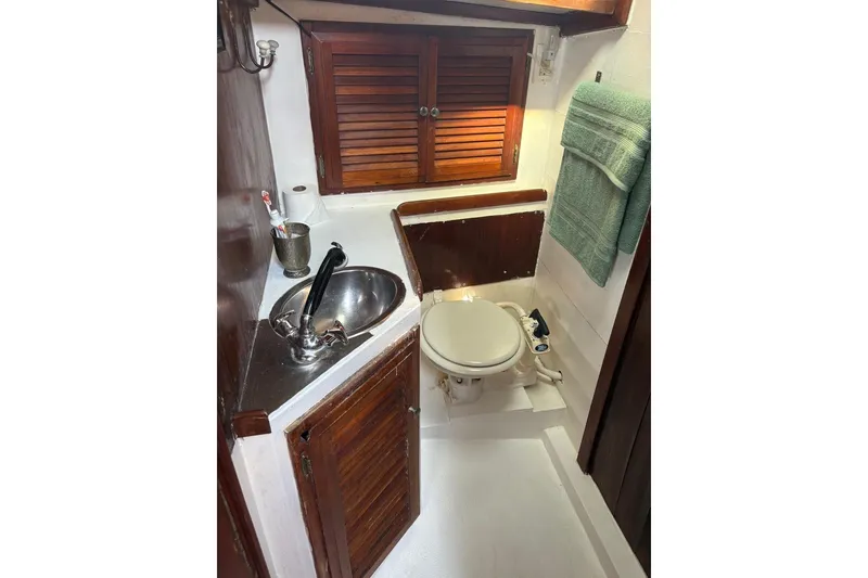 Slide: The Image of 1972 Islander 40MS yacht bathroom with sink, toilet, and wooden cabinetry. - 13