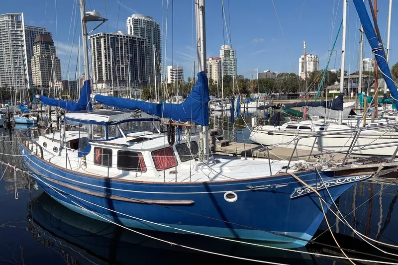 Slide: The Image of Blue 1972 Islander 40MS sailboat docked in urban marina with skyscrapers in background. - 2