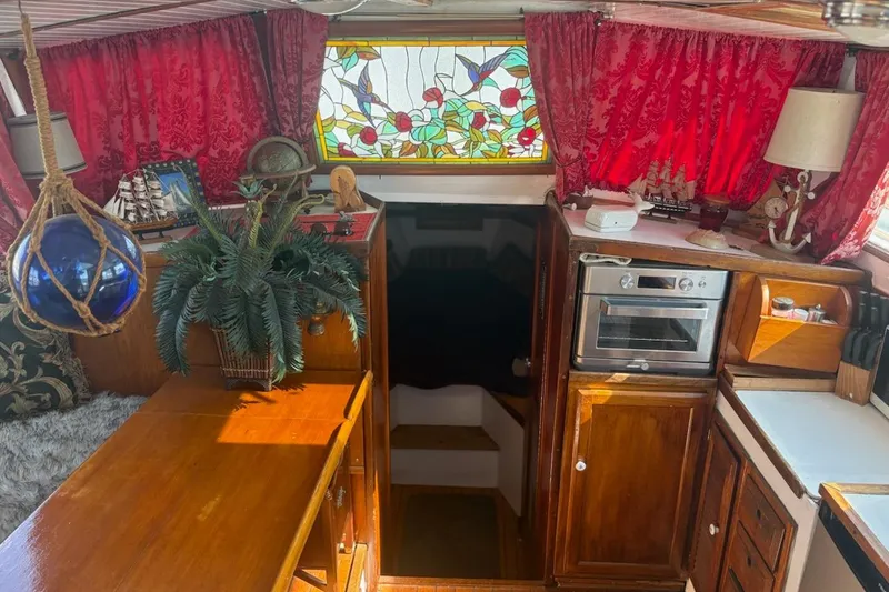 Slide: The Image of Interior of a 1972 Islander 40MS sailboat with wood cabinetry and vibrant red curtains. - 4