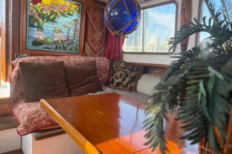 Slide: The Image of Cozy 1972 Islander 40MS yacht interior with stained glass, cushions, and wooden table. - 8