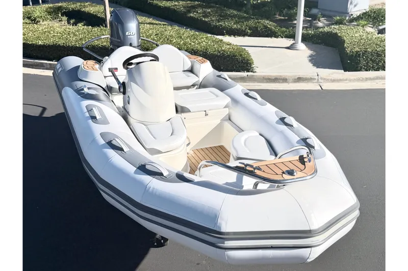 Slide: The Image of 2017 Avon Seasport 420 inflatable boat with seating and outboard motor, parked on pavement. - 2