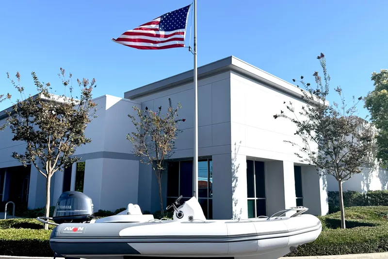 Slide: The Image of 2017 Avon Seasport 420 boat displayed outdoors with American flag and modern building backdrop. - 26
