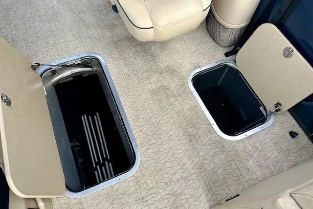 Slide: The Image of 2019 Barletta E22QC boat storage compartments with beige interior and open hatches. - 13