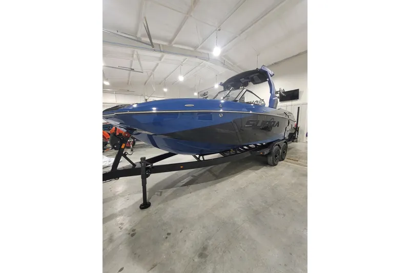 Slide: The Image of 2026 Supra SL 450 boat in a showroom, blue and black design on trailer. - 1