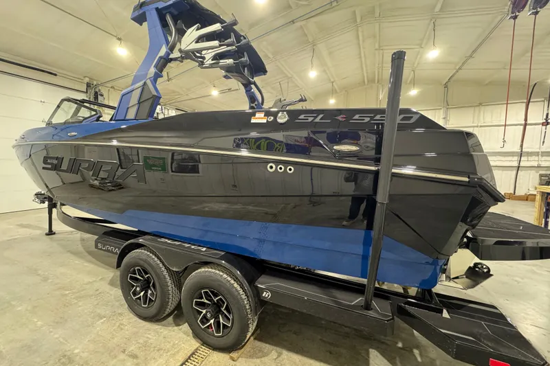 Slide: The Image of 2026 Supra SL 450 boat in a garage, featuring sleek black and blue design. - 2