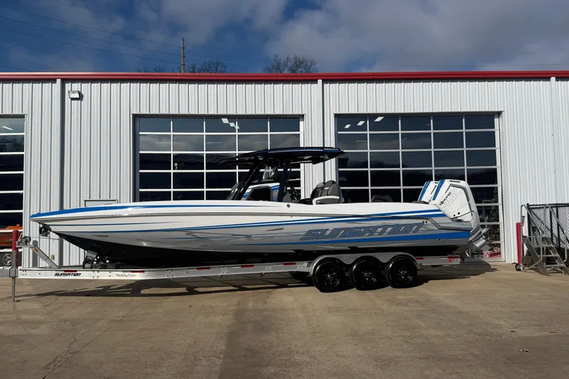 The Image of 2026 Sunsation 32 CCX boat on trailer, parked outside a garage. - 1