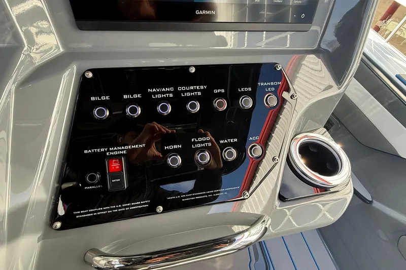Slide: The Image of Control panel of 2026 Sunsation 32 CCX boat with various switches and cup holder. - 12