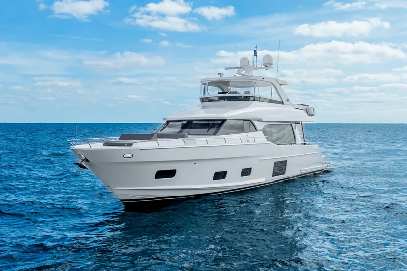 The Image of 2021 Ocean Alexander 70E Motoryacht cruising on blue ocean near city skyline. - 0