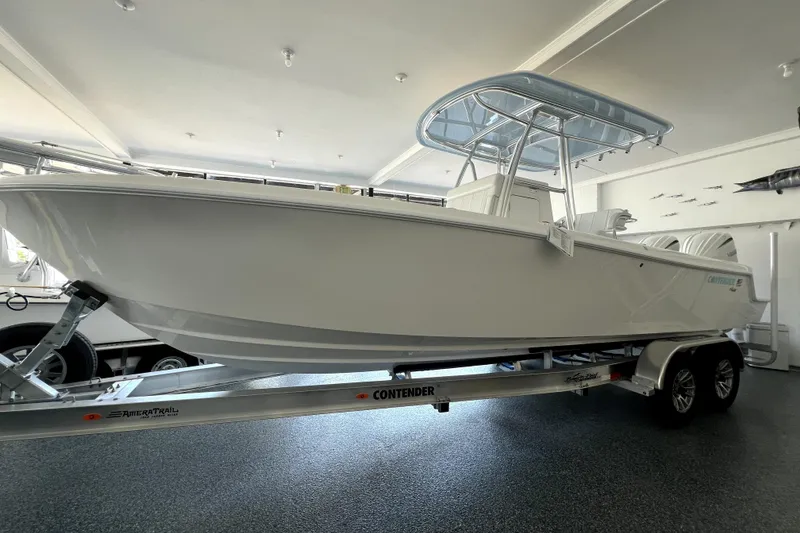Slide: The Image of 2026 Contender boat on trailer in showroom, featuring sleek design and T-top canopy. - 2