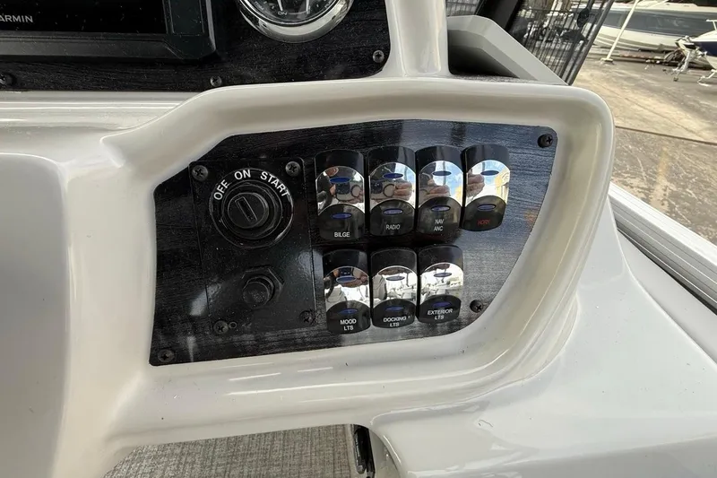 Slide: The Image of Control panel of 2026 Avalon LSZ Versatile Rear Bench Windshield boat with various switches. - 26
