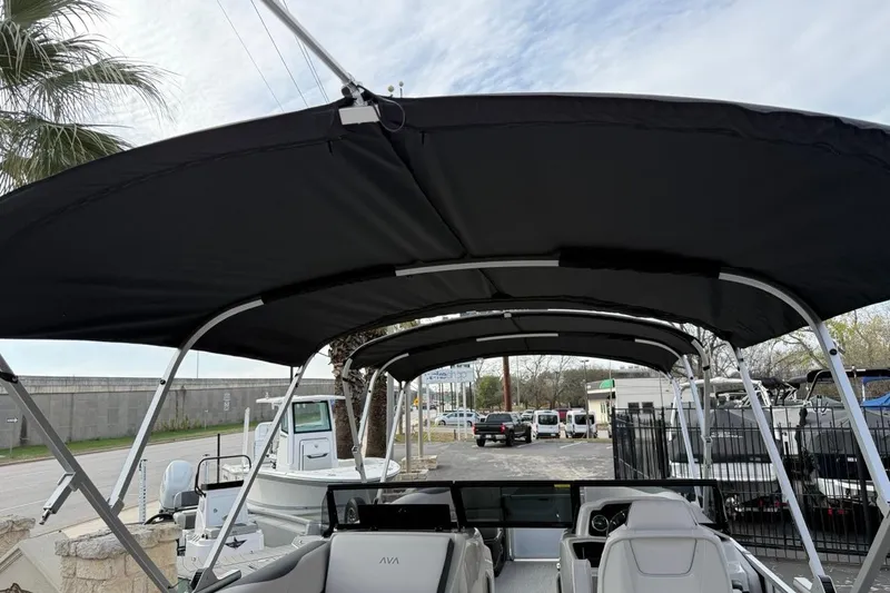 Slide: The Image of 2026 Avalon LSZ Versatile Rear Bench Windshield boat with canopy, parked outdoors. - 38