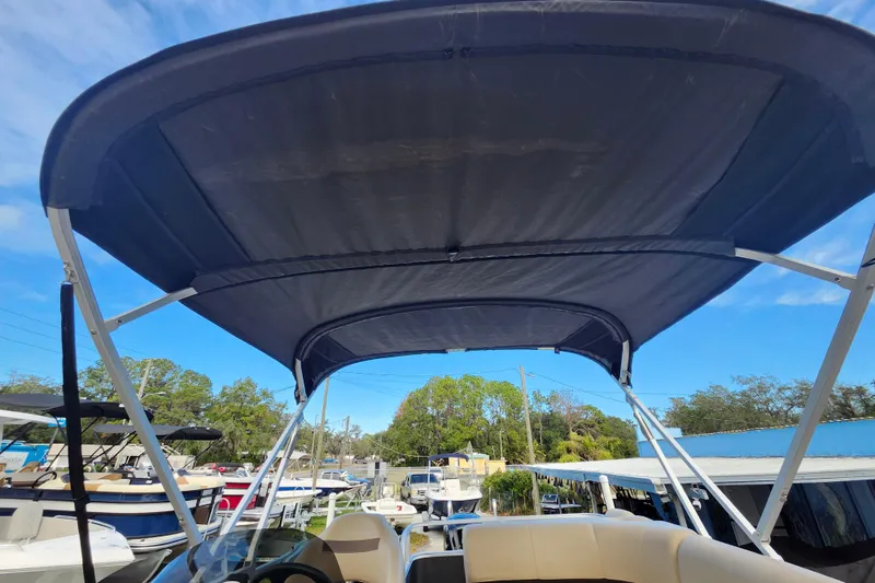 Slide: The Image of 2023 Sun Tracker Party Barge 18 DLX with canopy, docked under clear blue sky. - 13