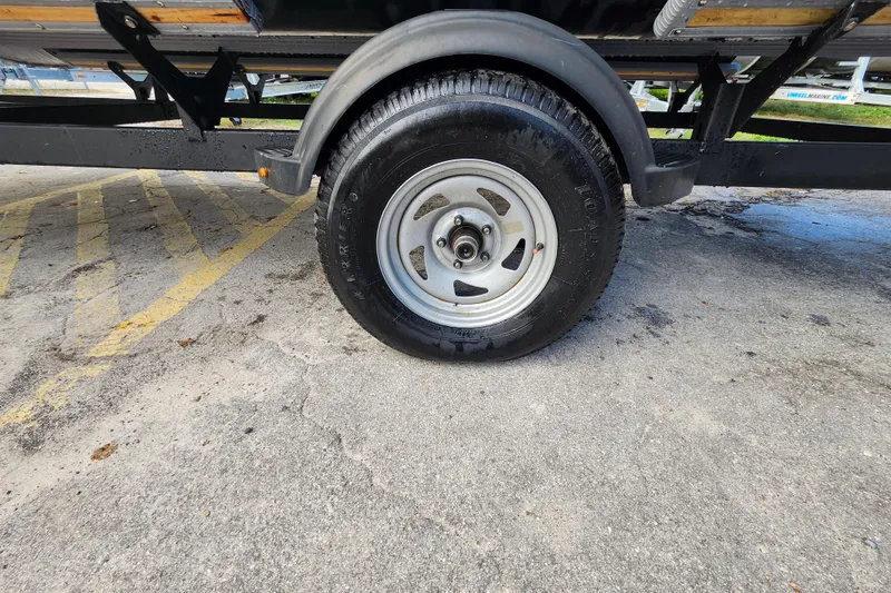 Slide: The Image of Trailer wheel of 2023 Sun Tracker Party Barge 18 DLX on pavement. - 16